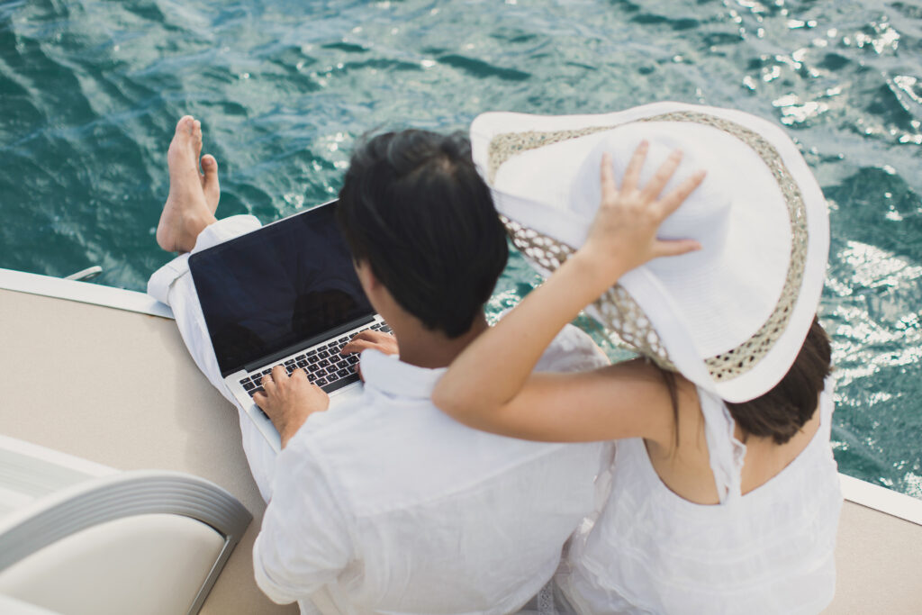 Two business people working with laptop on a sailing boat sailing trip